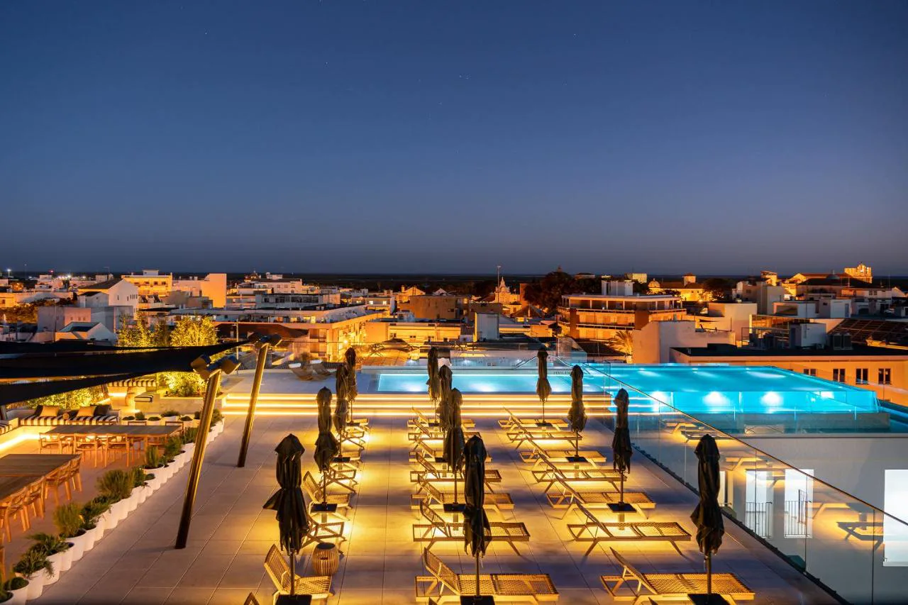 Piscina infinita en la azotea de 3HB Faro al atardecer sobre el centro de Faro