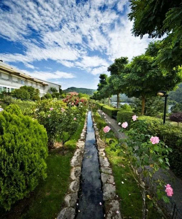 Canal de piedra con agua entre rosales y jardín, con vistas al río Miño, BALNEARIO ARNOIA