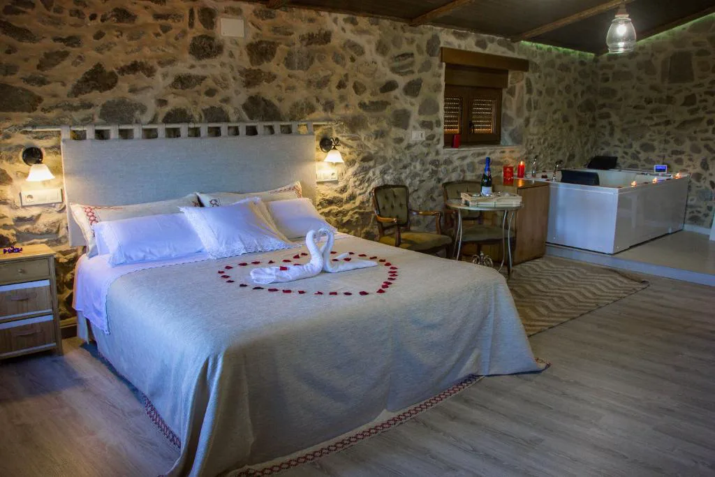 Suite con jacuzzi decorado con toallas en forma de cisne y corazón de pétalos de rosa, Casa das Fiadeiras de Nemiña