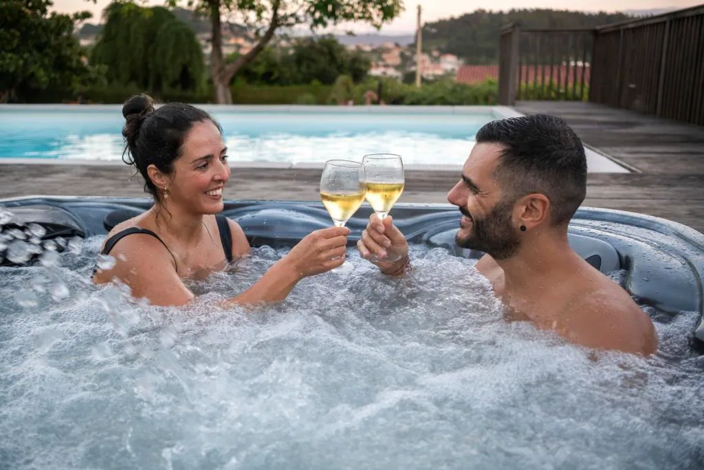 Jacuzzi exterior junto a la piscina con vistas al valle, brindis con copas de cava, Casa do Sear