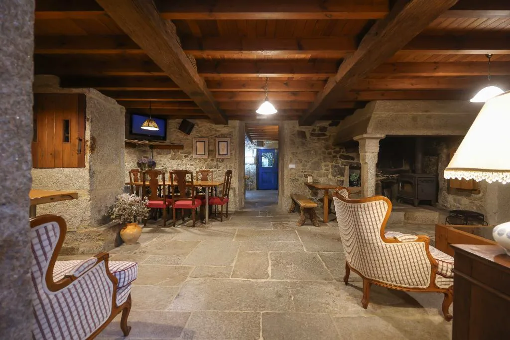 Salón de piedra con vigas de madera y gran chimenea tradicional, Casa Perfeuto Maria