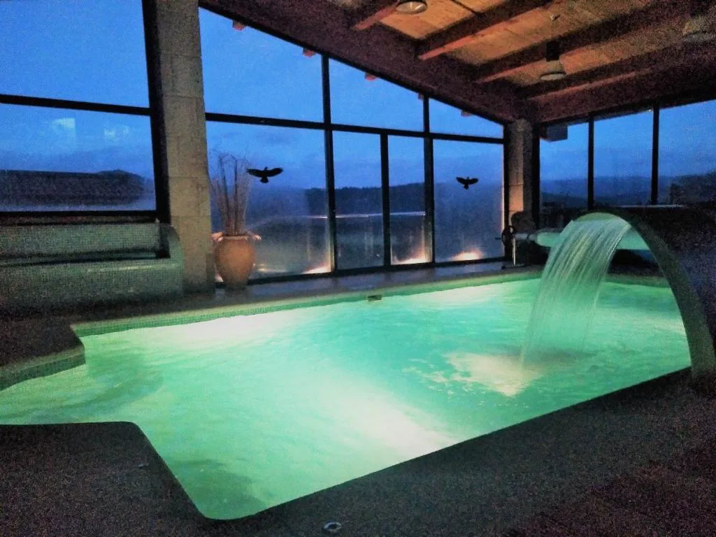Piscina interior privada con cascada iluminada al atardecer, Casa Spa en Montaña, Cerdedo