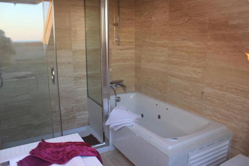 Bañera de hidromasaje privada de mármol con ventana al mar, Complejo Raeiros