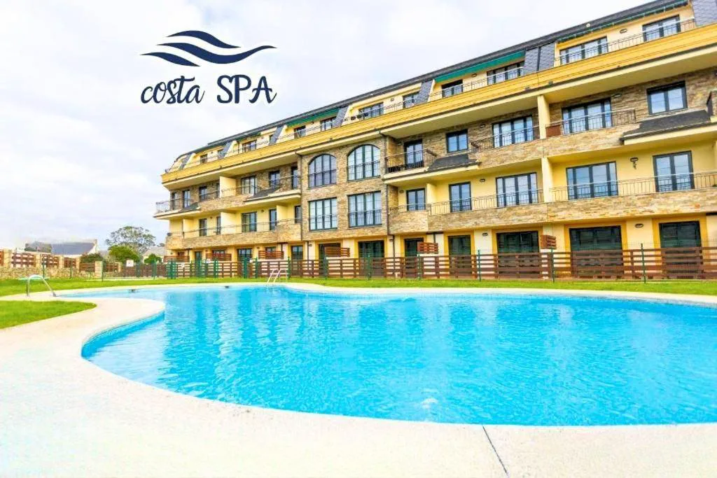 Piscina exterior del complejo Costa SPA con el edificio de apartamentos al fondo, San Miguel de Reinante