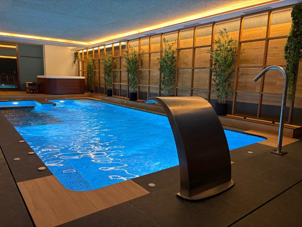 Piscina cubierta con cascada de hidromasaje y jacuzzi de pareja al fondo, Hotel SPA GBC Arcade