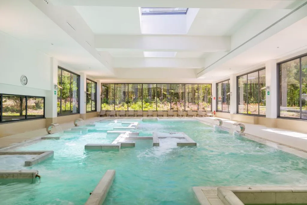 Gran piscina termal interior bajo cúpula de cristal con chorros y bancos de hidromasaje, Iberik Gran Balneario de Guitiriz