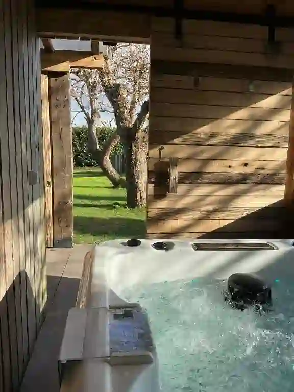 Jacuzzi de hidromasaje bajo techo de madera con puerta abierta al jardín, O Loureiro, Noia